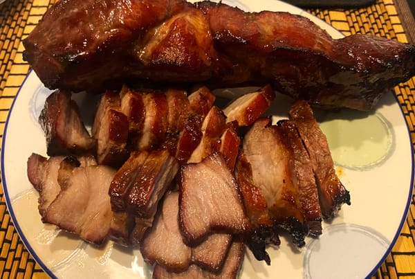 Homemade Chinese BBQ pork (char siu 叉燒) sliced on a plate with glossy caramelized glaze and charred edges.