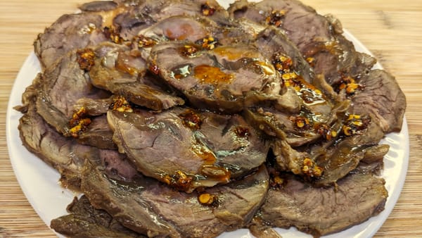 Close-up of thinly sliced Taiwanese braised beef shank served cold with chili oil drizzled on top.